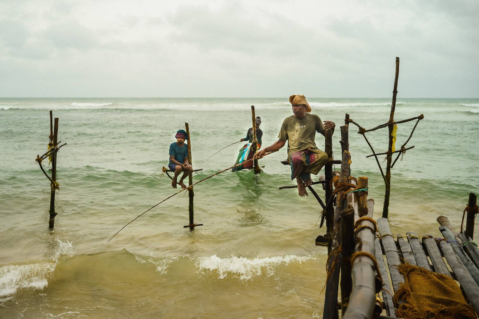 Stilt fishermen on wooden poles in the shallows of the Ahangama coast