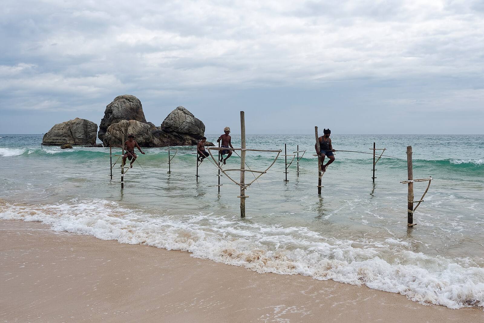 Stilt fishermen perched on poles in the surf on the south coast of Sri Lanka near Galle